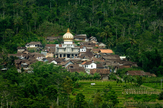 View of the Kebonsari village mosque with its golden dome surrounded by traditional houses and lush green forest in Temanggung Central Java Indonesia.