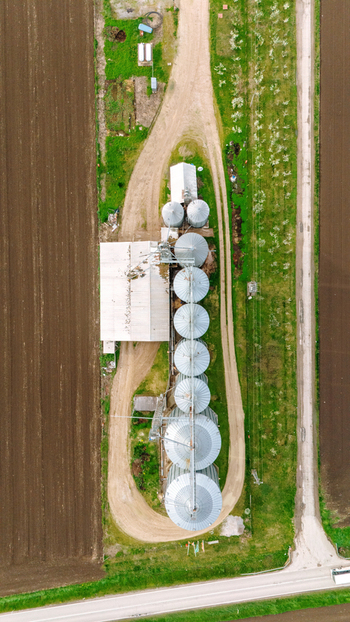 Aerial view of a series of metallic silos standing tall amidst agricultural fields casting shadows and reflecting the sky Sremska Mitrovica Vojvodina Serbia. Aerial view of a series of metallic silos standing tall amidst agricultural fields casting shadows and reflecting the sky Sremska Mitrovica Vojvodina Serbia.