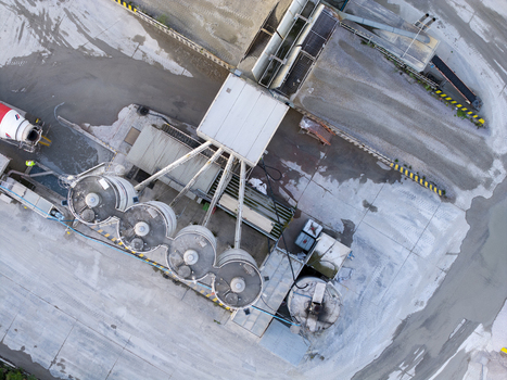 Aerial view of a concrete batching plant with industrial silos a cement mixer truck and paved grounds in an industrial area in Krakow Lesser Poland Voivode Poland. Aerial view of a concrete batching plant with industrial silos a cement mixer truck and paved grounds in an industrial area in Krakow Lesser Poland Voivode Poland.