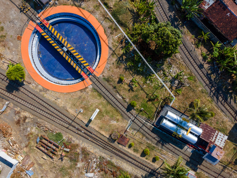 Aerial view of a railway turntable with a rotating bridge and tracks surrounded by storage tanks and vegetation in Cilacap Central Java Indonesia. Aerial view of a railway turntable with a rotating bridge and tracks surrounded by storage tanks and vegetation in Cilacap Central Java Indonesia.