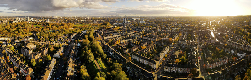 Aerial view of Finsbury Park surrounded by residential rooftops and the urban skyline under golden hour light in London England United Kingdom.