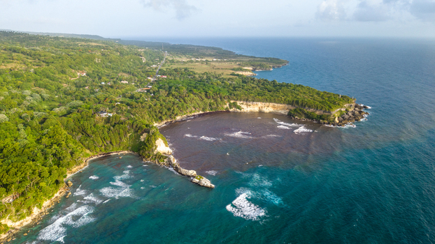 Aerial view of Cabo Frances Viejo featuring lush green cliffs dense vegetation and turquoise waters meeting the Atlantic Ocean in Cabrera Maria Trinidad Sanchez Dominican Republic.