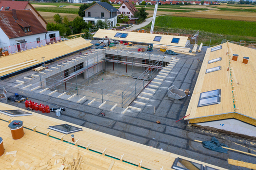 Igensdorf Germany 11 May 2024 Aerial view of the construction of a residential building featuring a central courtyard wooden roof structures and scaffolding. Igensdorf Germany 11 May 2024 Aerial view of the construction of a residential building featuring a central courtyard wooden roof structures and scaffolding.