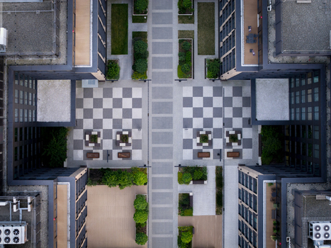 Aerial view of a modern residential complex with a checkered courtyard landscaped green spaces and geometric building architecture in Poland. Aerial view of a modern residential complex with a checkered courtyard landscaped green spaces and geometric building architecture in Poland.