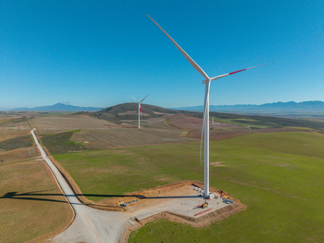 Aerial view of wind turbines standing in green fields under a clear blue sky with rolling hills in the background Swellendam Western Cape South Africa. Aerial view of wind turbines standing in green fields under a clear blue sky with rolling hills in the background Swellendam Western Cape South Africa.