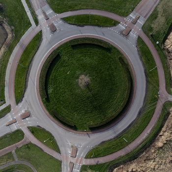 Aerial view of a roundabout a green oasis encircled by gray roads and red brick paths Overgooi Flevoland Netherlands. Aerial view of a roundabout a green oasis encircled by gray roads and red brick paths Overgooi Flevoland Netherlands.