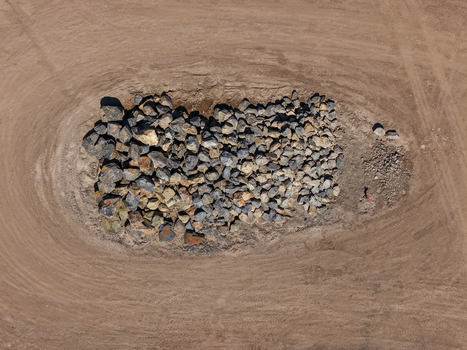 Aerial view of a large pile of rocks and boulders situated in the center of a cleared dirt field with visible tire tracks in Kilsyth Victoria Australia. Aerial view of a large pile of rocks and boulders situated in the center of a cleared dirt field with visible tire tracks in Kilsyth Victoria Australia.