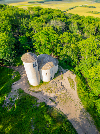 Aerial view of the historic Romanesque Rotunda of Saint George atop the forested Rip Mountain surrounded by lush trees and golden fields in Mnetes Usti nad Labem Region Czechia. Aerial view of the historic Romanesque Rotunda of Saint George atop the forested Rip Mountain surrounded by lush trees and golden fields in Mnetes Usti nad Labem Region Czechia.