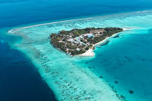Aerial view of the tropical island of Vaanee surrounded by vibrant coral reefs and turquoise lagoon waters in Vaanee Dhaalu Atoll Maldives. Aerial view of the tropical island of Vaanee surrounded by vibrant coral reefs and turquoise lagoon waters in Vaanee Dhaalu Atoll Maldives.
