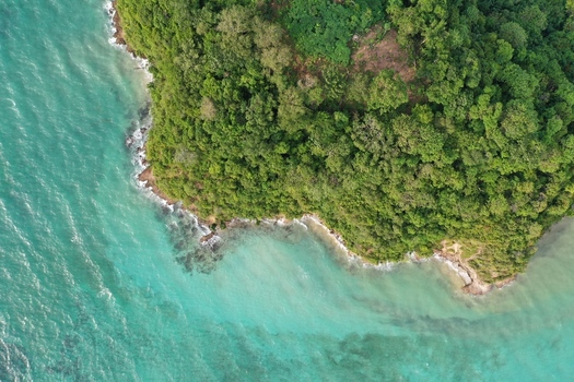Aerial view of the lush green coastline of Pulau Maginti with turquoise waters and rocky shorelines in Maginti South East Sulawesi Indonesia.