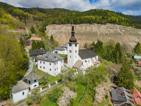 Aerial view of the Church of the Conversion of the Lord and traditional houses surrounded by lush green hills in Spania Dolina Banska Bystrica Region Slovakia.