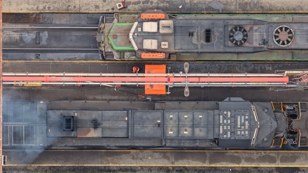 Aerial view of two freight locomotives parked in a rail yard with a worker in an orange vest standing between them in Denver Colorado United States. Aerial view of two freight locomotives parked in a rail yard with a worker in an orange vest standing between them in Denver Colorado United States.