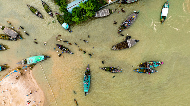 Aerial view of Baish Mowza Sarak Bazar with numerous traditional wooden boats carrying people and goods along the river in Nabinagar Chittagong Division Bangladesh. Aerial view of Baish Mowza Sarak Bazar with numerous traditional wooden boats carrying people and goods along the river in Nabinagar Chittagong Division Bangladesh.