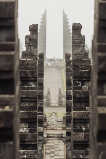 View of the tiered stone gates of Cetho Temple leading through a misty pathway with traditional Hindu architecture in Kecamatan Jenawi Jawa Tengah Indonesia. View of the tiered stone gates of Cetho Temple leading through a misty pathway with traditional Hindu architecture in Kecamatan Jenawi Jawa Tengah Indonesia.