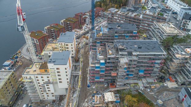 Aerial view of a construction site with modern apartment buildings tower cranes scaffolding and waterfront access in Sweden. Aerial view of a construction site with modern apartment buildings tower cranes scaffolding and waterfront access in Sweden.