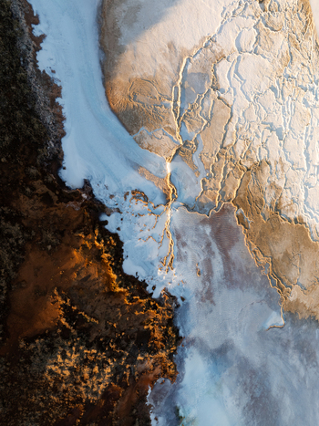 Aerial view of the geothermal landscape of Reykjanes with rugged volcanic terrain mineral deposits and steam vents illuminated by golden hour light in Grindavikurbaer Iceland. Aerial view of the geothermal landscape of Reykjanes with rugged volcanic terrain mineral deposits and steam vents illuminated by golden hour light in Grindavikurbaer Iceland.