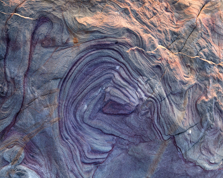 View of geological rock formations with purple swirling patterns and layered textures in Calafuria Toscana Italy.