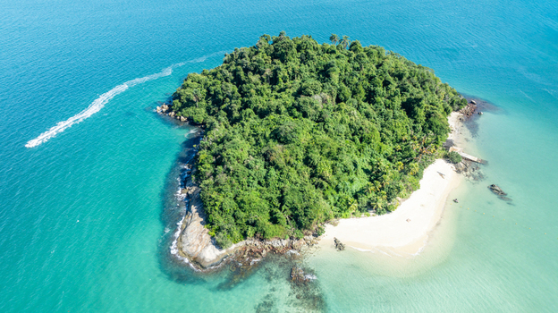 Aerial view of a lush tropical island with a white sandy beach surrounded by turquoise waters and rocky shores in Angra dos Reis Rio de Janeiro Brazil.