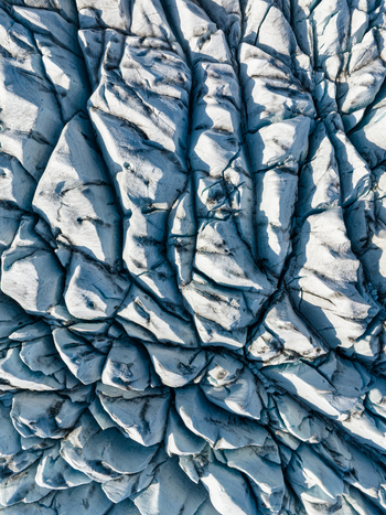 Aerial view of the intricate patterns of deep blue crevasses and jagged ice formations on a glacier surface in Iceland. Aerial view of the intricate patterns of deep blue crevasses and jagged ice formations on a glacier surface in Iceland.