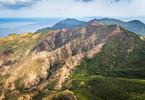 Aerial view of Castello del Volterraio nestled in the rugged mountainous landscape of Elba with Mediterranean vegetation and the sea in the distance in Portoferraio Toscana Italy.