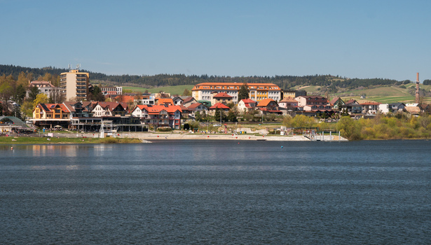 Aerial view of Namestovo town and Oravska priehrada dam featuring colorful buildings lush trees and calm water under a clear blue sky in Namestovo Zilina Region Slovakia. Aerial view of Namestovo town and Oravska priehrada dam featuring colorful buildings lush trees and calm water under a clear blue sky in Namestovo Zilina Region Slovakia.