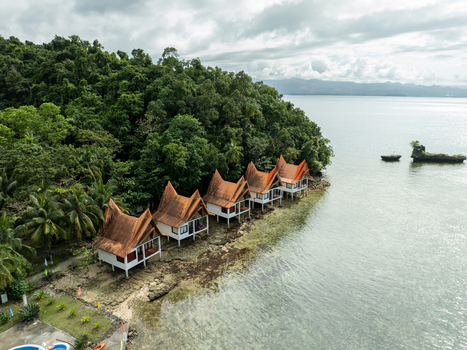 Aerial view of stilt bungalows with orange roofs nestled along the lush coastline of Bucas Grande in Siargao Philippines. Aerial view of stilt bungalows with orange roofs nestled along the lush coastline of Bucas Grande in Siargao Philippines.