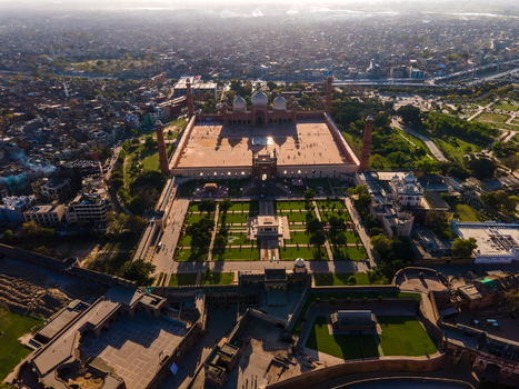 Aerial view of Badshahi Mosque with its large courtyard minarets and surrounding gardens set against the dense urban landscape of the city Lahore Punjab Pakistan. Aerial view of Badshahi Mosque with its large courtyard minarets and surrounding gardens set against the dense urban landscape of the city Lahore Punjab Pakistan.