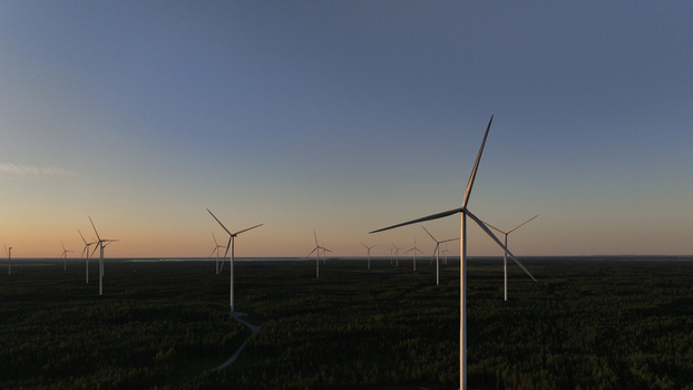 Aerial view of Metsalamminkangas Tuulipuisto wind farm with large turbines rising above the dense forest during golden hour in Siikalatva Pohjois Pohjanmaa Finland. Aerial view of Metsalamminkangas Tuulipuisto wind farm with large turbines rising above the dense forest during golden hour in Siikalatva Pohjois Pohjanmaa Finland.