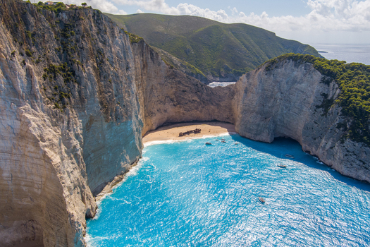 Aerial view of Navagio Beach featuring the iconic shipwreck on the sandy shore surrounded by towering limestone cliffs and vibrant turquoise waters in Zakynthos Navagio Greece.