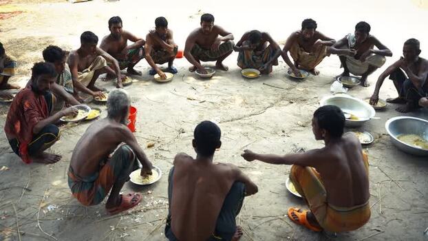 View of men sitting in a circle eating together in Natore Bangladesh. View of men sitting in a circle eating together in Natore Bangladesh.