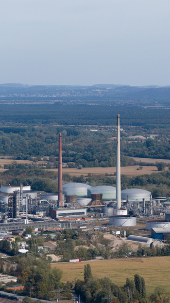 Aerial view of Mineralolraffinerie Oberrhein with tall chimneys industrial storage tanks and complex infrastructure surrounded by fields and trees in Karlsruhe Baden Wurttemberg Germany. Aerial view of Mineralolraffinerie Oberrhein with tall chimneys industrial storage tanks and complex infrastructure surrounded by fields and trees in Karlsruhe Baden Wurttemberg Germany.