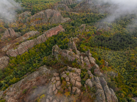 Aerial view of the Belogradchik Rocks featuring unique sandstone and conglomerate formations surrounded by a dense autumn forest with patches of mist in Belogradchik Vidin Bulgaria. Aerial view of the Belogradchik Rocks featuring unique sandstone and conglomerate formations surrounded by a dense autumn forest with patches of mist in Belogradchik Vidin Bulgaria.