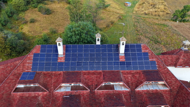 Aerial view of solar panels installed on the red shingled roof of the Brzece Sports Centar surrounded by green hills in Brzece Rasina District Serbia.