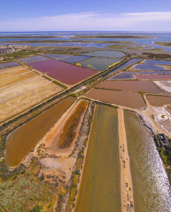 Aerial view of the colorful salt evaporation ponds at Salinas do Grelha with geometric patterns and coastal landscape in Olhao Faro Portugal. Aerial view of the colorful salt evaporation ponds at Salinas do Grelha with geometric patterns and coastal landscape in Olhao Faro Portugal.