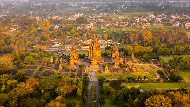 Aerial view of Prambanan Temple complex with its towering stone spires surrounded by lush green trees during golden hour Kecamatan Prambanan Daerah Istimewa Yogya Indonesia. Aerial view of Prambanan Temple complex with its towering stone spires surrounded by lush green trees during golden hour Kecamatan Prambanan Daerah Istimewa Yogya Indonesia.