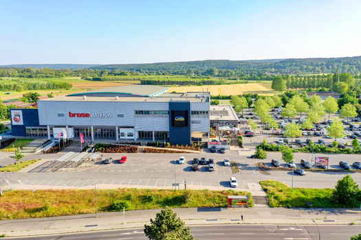 Bamberg Germany 02 May 2026 Aerial view of Brose Arena multi purpose indoor sports stadium with parking lots and surrounding green fields under a clear sky.