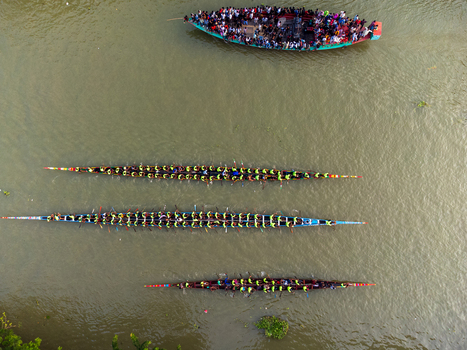 Aerial view of vibrant dragon boats cutting through the murky waters complemented by a spectator filled boat Gopalganj Dhaka Division Bangladesh. Aerial view of vibrant dragon boats cutting through the murky waters complemented by a spectator filled boat Gopalganj Dhaka Division Bangladesh.