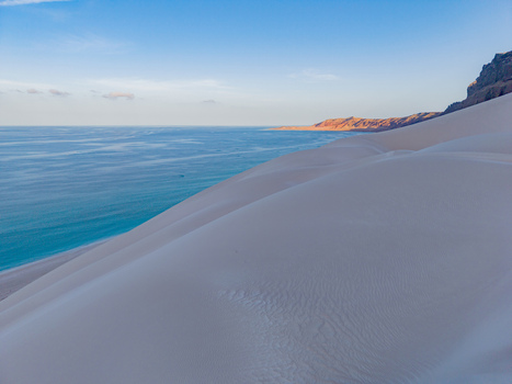 Aerial view of the stark white dunes meet the turquoise ocean contrasting with the rugged cliffs Erissel Socotra Yemen. Aerial view of the stark white dunes meet the turquoise ocean contrasting with the rugged cliffs Erissel Socotra Yemen.