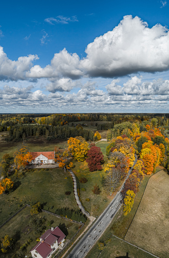 Aerial view of Sigulda in autumn featuring a historic building vibrant fall foliage a winding road and lush fields under a blue sky in Sigulda Sigulda Municipality Latvia. Aerial view of Sigulda in autumn featuring a historic building vibrant fall foliage a winding road and lush fields under a blue sky in Sigulda Sigulda Municipality Latvia.