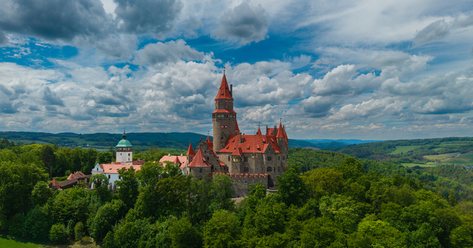 Aerial view of Bouzov Castle with its iconic red roofed towers and stone walls nestled among lush green forests under a dramatic cloudy sky Bouzov Olomoucky kraj Czechia. Aerial view of Bouzov Castle with its iconic red roofed towers and stone walls nestled among lush green forests under a dramatic cloudy sky Bouzov Olomoucky kraj Czechia.