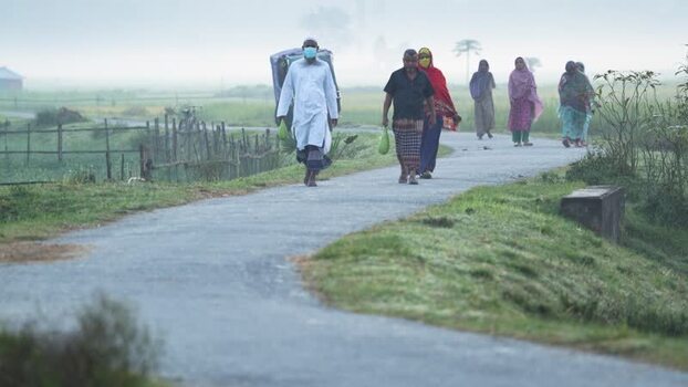 View of people walking on a rural road in Bogura Bangladesh.