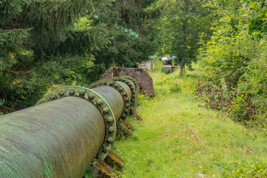 View of the Jasenie Hydroelectric Power Plant featuring a large industrial pipeline running through a lush green forest in Jasenie Banska Bystrica Regio Slovakia.