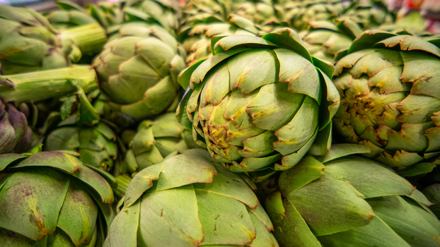 View of fresh green artichokes stacked in a market display in California City California United States. View of fresh green artichokes stacked in a market display in California City California United States.