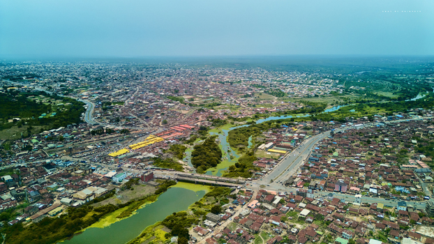 Aerial view of the vibrant cityscape where the muddy Ogun River meanders through dense buildings and lush greenery Abeokuta Ogun State Nigeria.