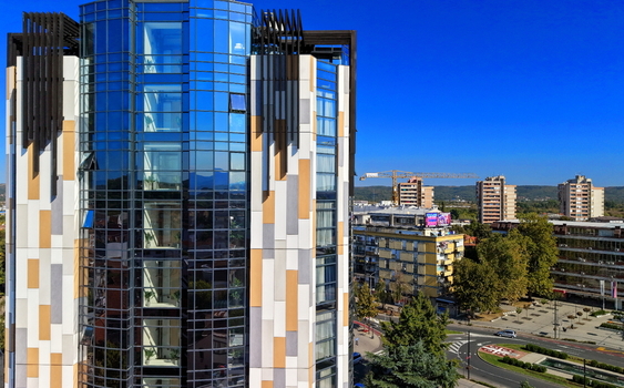 Aerial view of a modern glass and panel clad building in the city center with surrounding urban infrastructure and trees in Krusevac Rasina District Serbia. Aerial view of a modern glass and panel clad building in the city center with surrounding urban infrastructure and trees in Krusevac Rasina District Serbia.