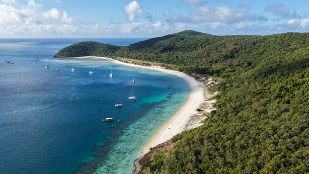 Aerial view of Haslewood Island featuring a white sand beach turquoise coral reef waters and sailboats anchored in the bay Whitsundays Queensland Australia. Aerial view of Haslewood Island featuring a white sand beach turquoise coral reef waters and sailboats anchored in the bay Whitsundays Queensland Australia.
