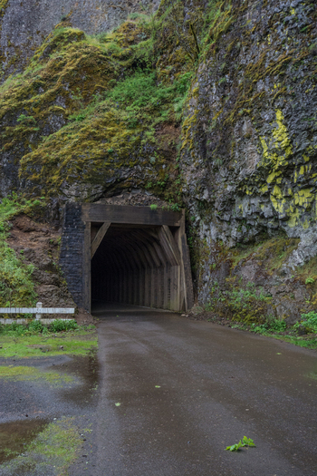 View of the historic tunnel entrance carved into a mossy basalt cliff face along the Columbia River Gorge trail in Hood River Oregon United States.