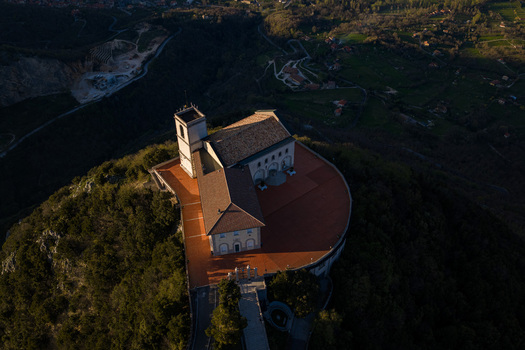 Aerial view of Santuario del Santissimo Salvatore on a forested hilltop with its large terrace and bell tower under warm light Montella Campania Italy. Aerial view of Santuario del Santissimo Salvatore on a forested hilltop with its large terrace and bell tower under warm light Montella Campania Italy.