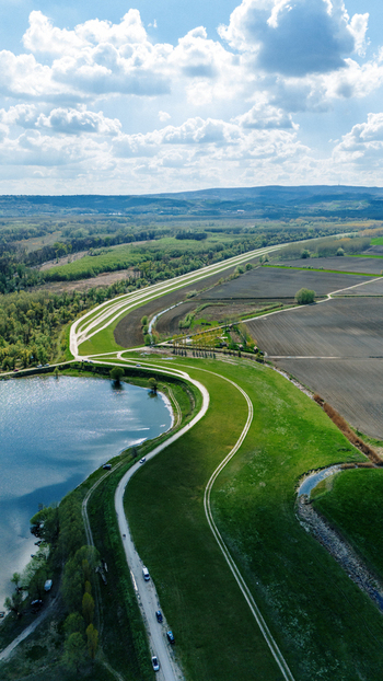 Aerial view of the vibrant green embankment curving sinuously along the water s edge contrasting with the dark earth and the distant forest Kovilj Vojvodina Serbia. Aerial view of the vibrant green embankment curving sinuously along the water s edge contrasting with the dark earth and the distant forest Kovilj Vojvodina Serbia.