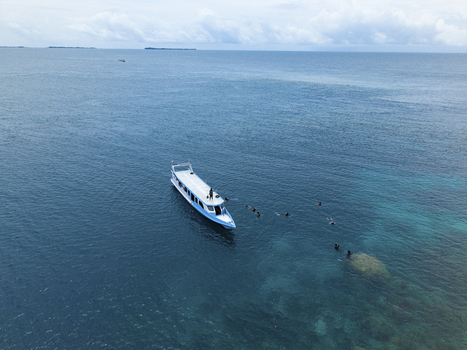 Aerial view of a brilliant white and blue boat floating on the turquoise sea near Cemara Kecil Snorkeling Spot Karimunjawa Central Java Indonesia.